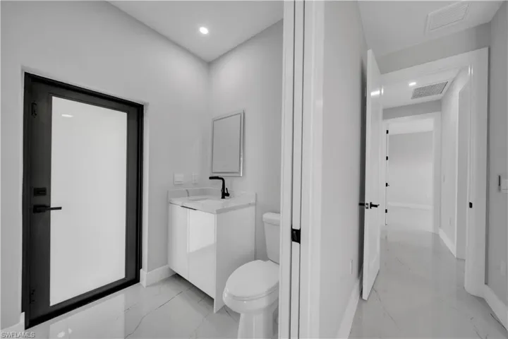 Modern bathroom featuring a contemporary vanity with a white countertop and black faucet, a framed mirror, and recessed lighting