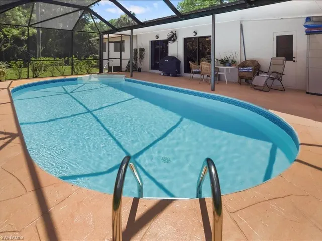 Outdoor pool featuring a sunroom, a patio, a lanai, and a grill