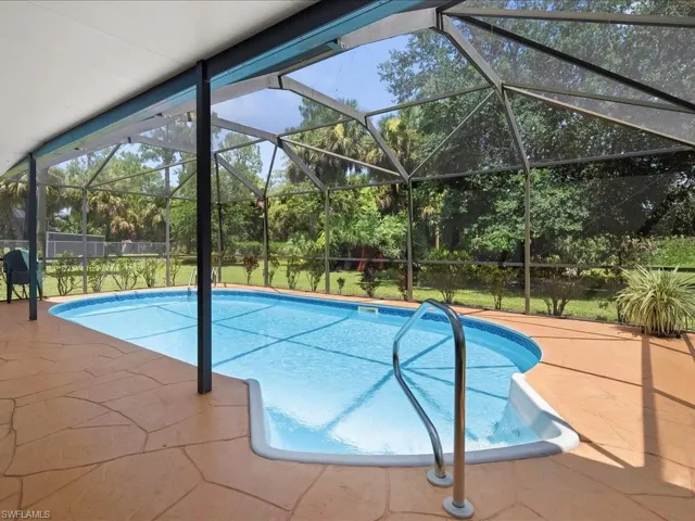 Outdoor pool with glass enclosure, a sunroom, and a patio area