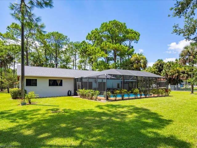 Rear view of house featuring a sunroom, an outdoor pool, a lanai, and a yard