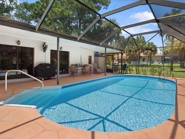 Outdoor pool with a lanai, a patio, a sunroom, and a grill