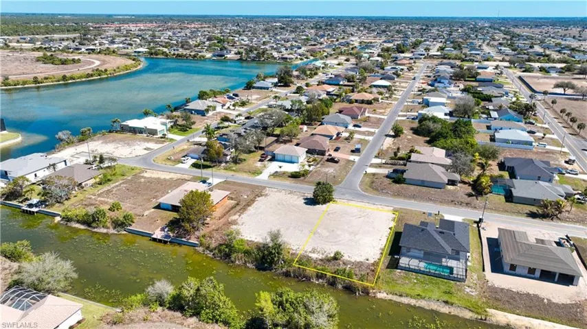 Aerial view of residential area with property parcel outlined and a nearby body of water