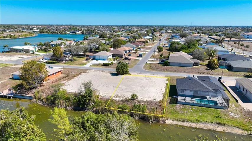 Aerial view of residential area with a large body of water and property boundaries highlighted