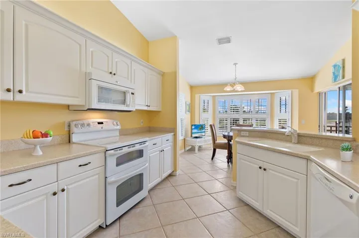 Kitchen featuring a sink, visible vents, white cabinets, and white appliances
