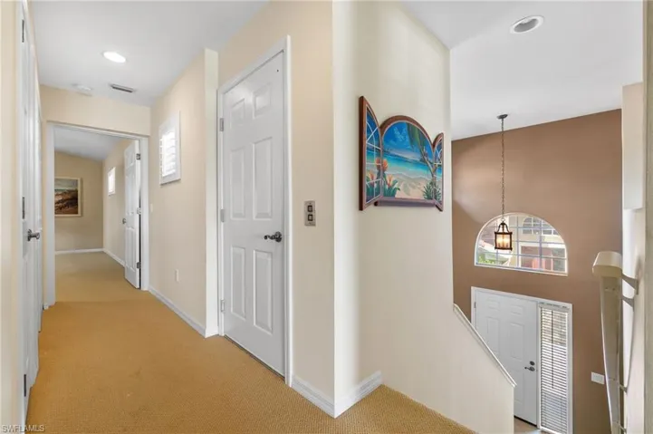 Hallway with light carpet, baseboards, and a wealth of natural light