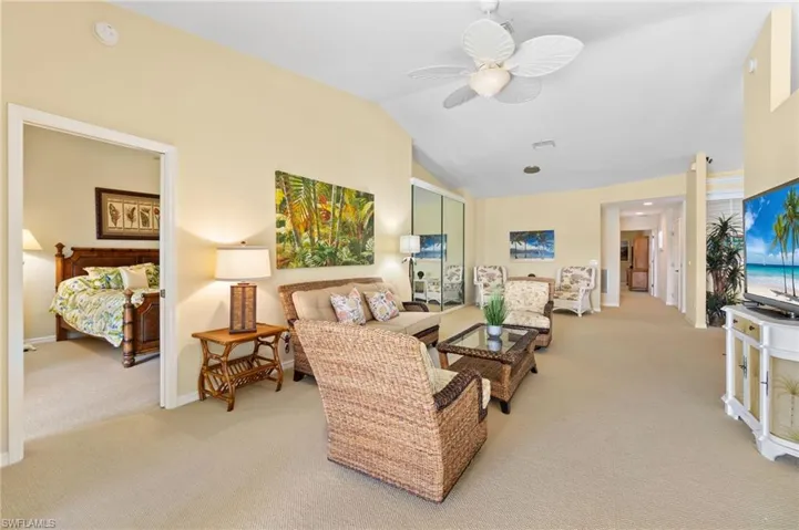 Living room with carpet flooring, baseboards, vaulted ceiling, and a ceiling fan