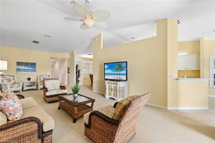 Living area featuring visible vents, ceiling fan, light colored carpet, and baseboards