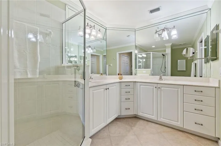 Bathroom with a shower stall, ornamental molding, visible vents, tile patterned flooring, and a sink