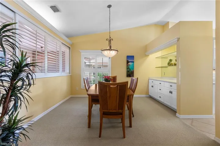 Dining space featuring visible vents, baseboards, light colored carpet, and lofted ceiling