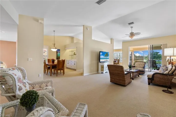 Living room with light carpet, visible vents, a ceiling fan, and lofted ceiling