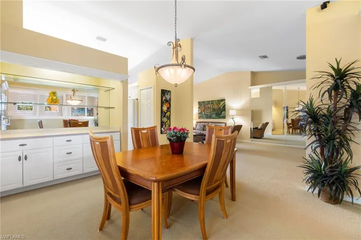 Dining space featuring light carpet, visible vents, and vaulted ceiling
