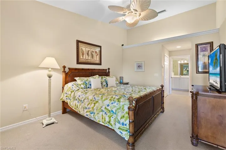 Bedroom with light carpet, baseboards, a ceiling fan, and connected bathroom