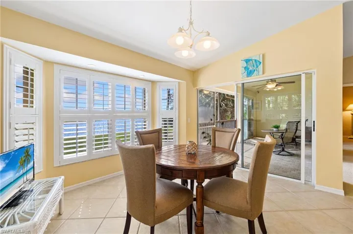 Dining room featuring baseboards, light tile patterned flooring, and vaulted ceiling