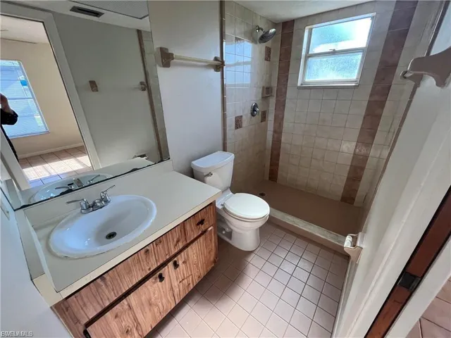 Bathroom with light tile patterned floors, vanity, and a stall shower