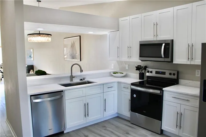 Kitchen with appliances with stainless steel finishes, white cabinets, and light wood-style flooring