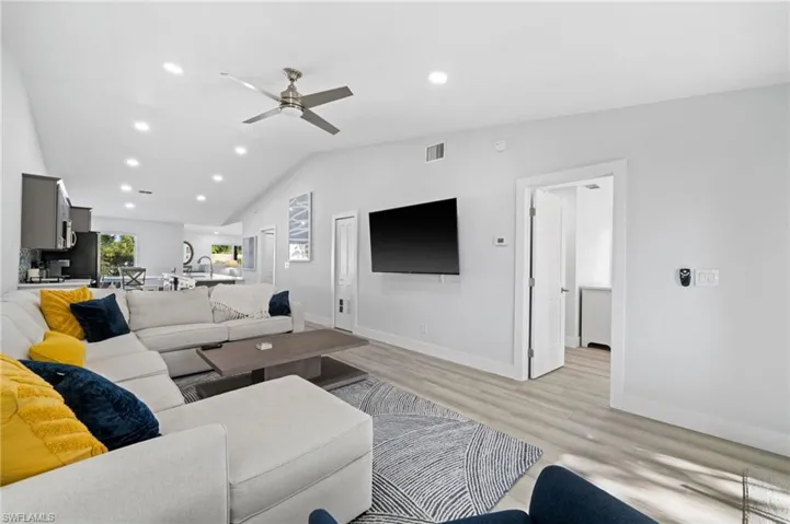 Living area with light wood-type flooring, a ceiling fan, recessed lighting, and vaulted ceiling