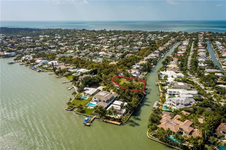 Aerial view of residential area with a large body of water and property boundaries highlighted
