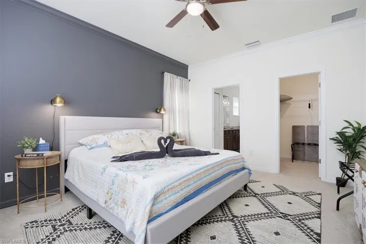 Owners Bedroom featuring light colored carpet, crown molding, ceiling fan, a spacious closet, and ensuite bathroom
