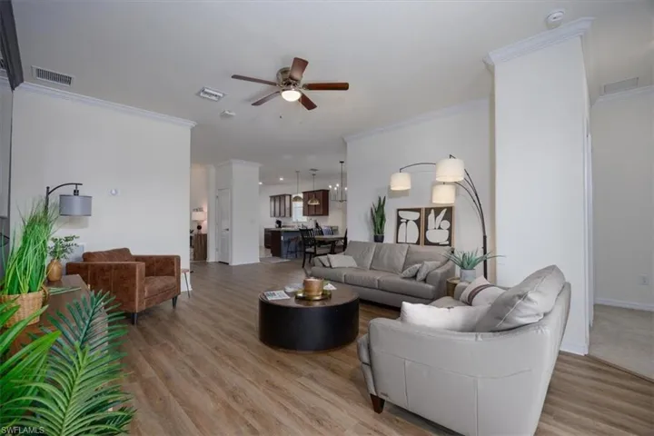 Living room with ornamental molding, easy care floors, and ceiling fan