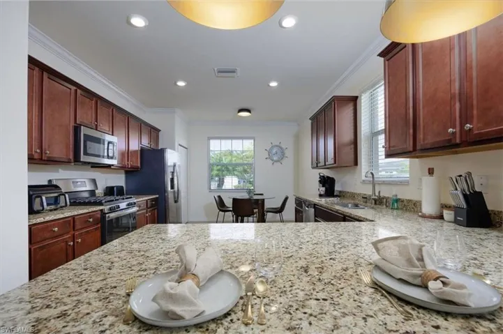 Kitchen featuring ornamental molding, light stone countertops, appliances with stainless steel finishes, and recessed lighting