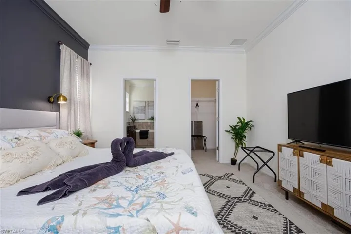 Owners Bedroom featuring a walk in closet, carpet, crown molding, ceiling fan, and ensuite bath