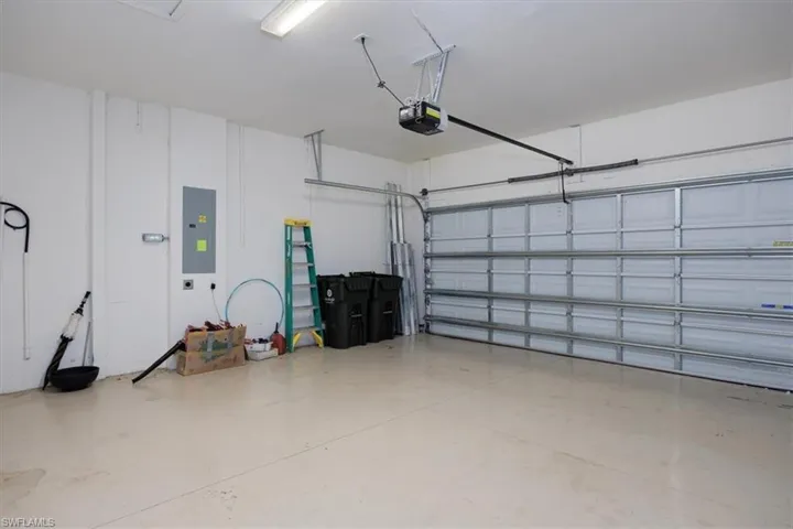 Garage featuring electric panel and an on demand Hot water hearter, electric car charging station and storm rated & reinforced garage door system.