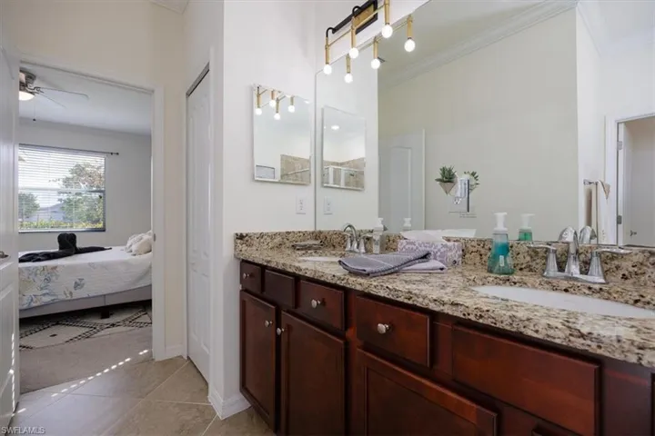 Full bath featuring ornamental molding, double vanity, ceiling fan, light tile patterned floors, and ensuite bath