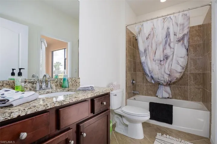 Bathroom with vanity, shower / tub combo with curtain, and light tile patterned floors with acces to Lanai