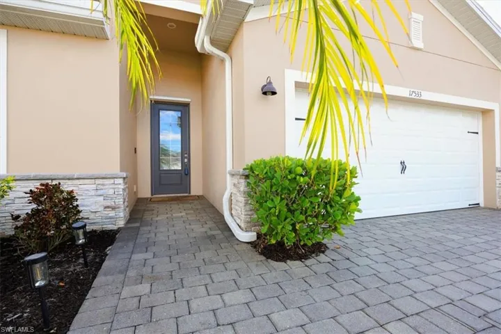 Entrance to property with a garage, stucco siding, and decorative driveway
