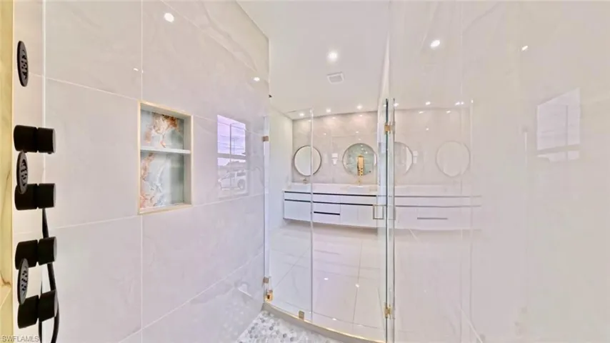 Bathroom with a stall shower, recessed lighting, double vanity, and tile walls
