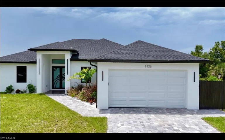 View of front of house with a shingled roof, decorative driveway, stucco siding, and an attached garage