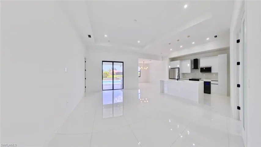 Empty room featuring a raised ceiling, a chandelier, light tile patterned floors, and recessed lighting