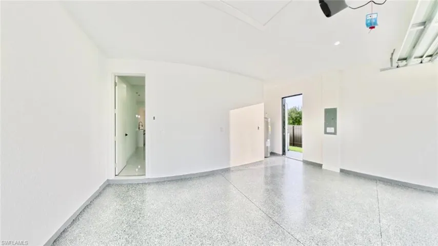 Garage featuring electric panel and baseboards