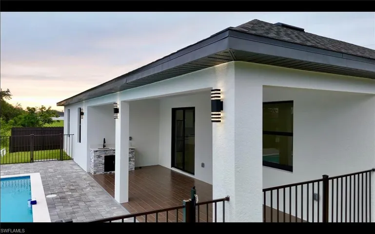Back of property at dusk with stucco siding and area for grilling