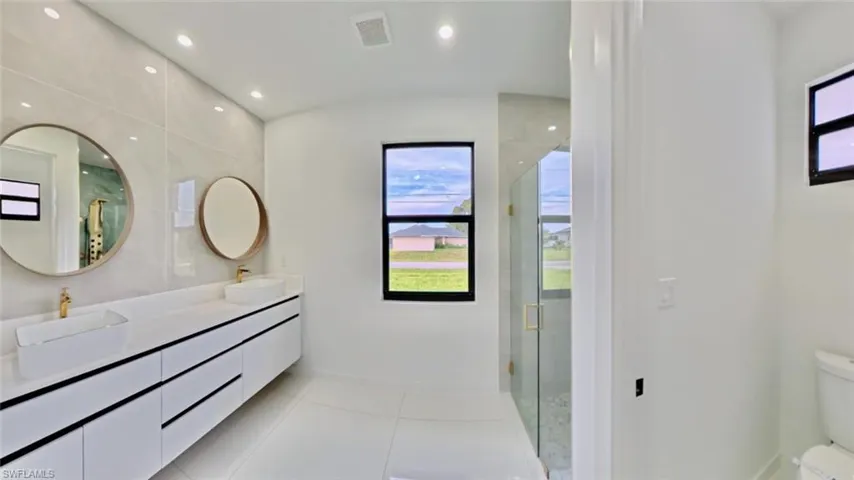 Bathroom with double vanity, a shower stall, recessed lighting, and light tile patterned flooring