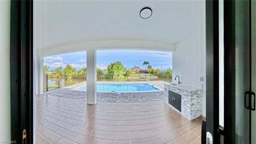 View of pool with a patio, a water view, and an outdoor kitchen