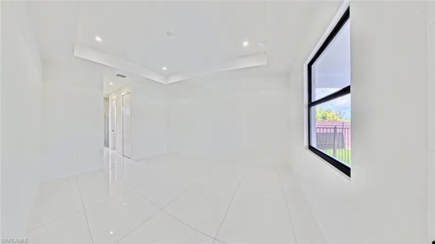 Unfurnished room with light tile patterned floors, recessed lighting, and a tray ceiling