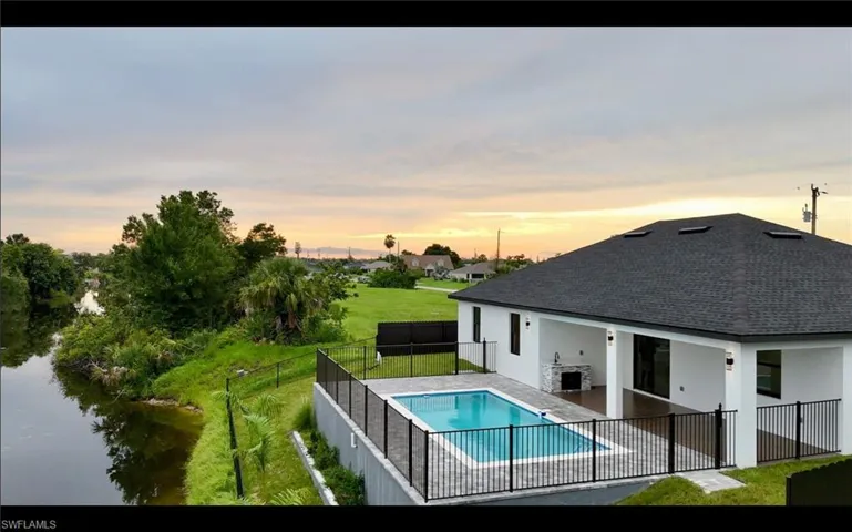 View of pool with a fenced backyard, a patio area, and a water view