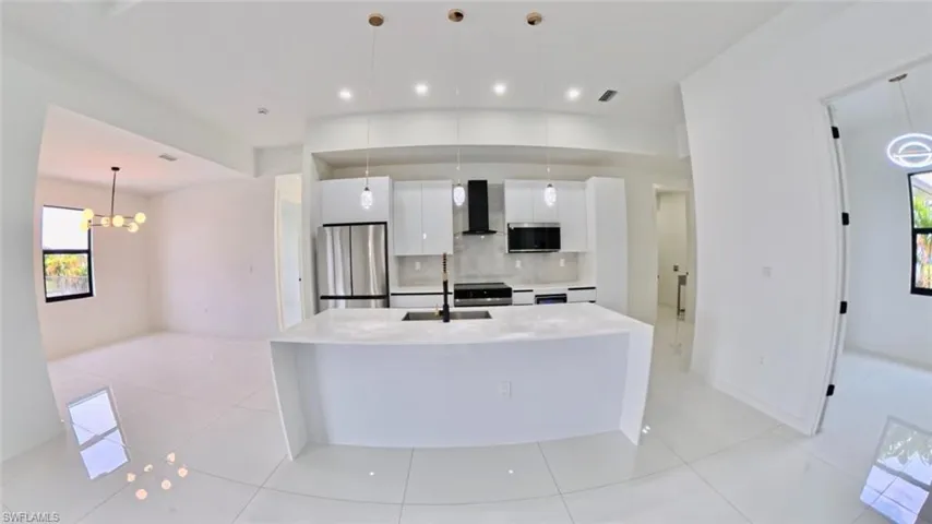 Kitchen with healthy amount of natural light, white cabinetry, decorative light fixtures, appliances with stainless steel finishes, and recessed lighting