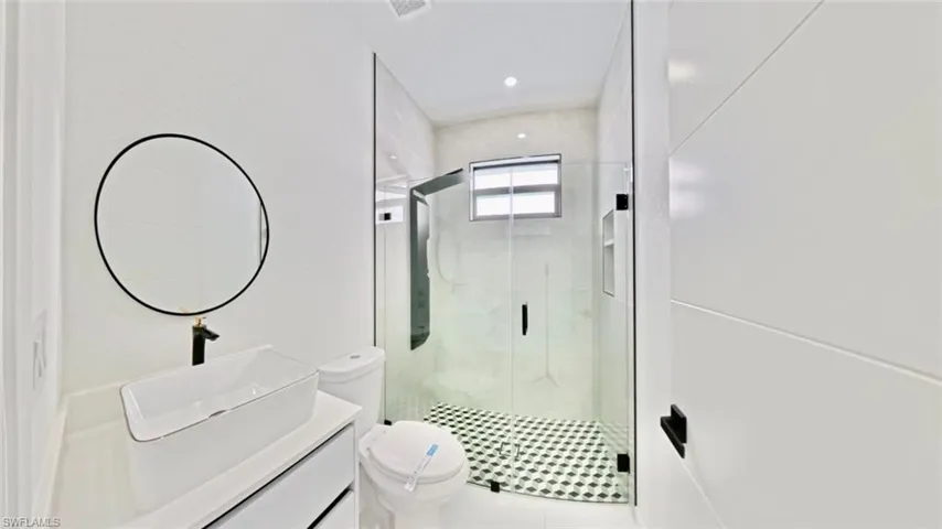 Bathroom with a stall shower, vanity, and recessed lighting