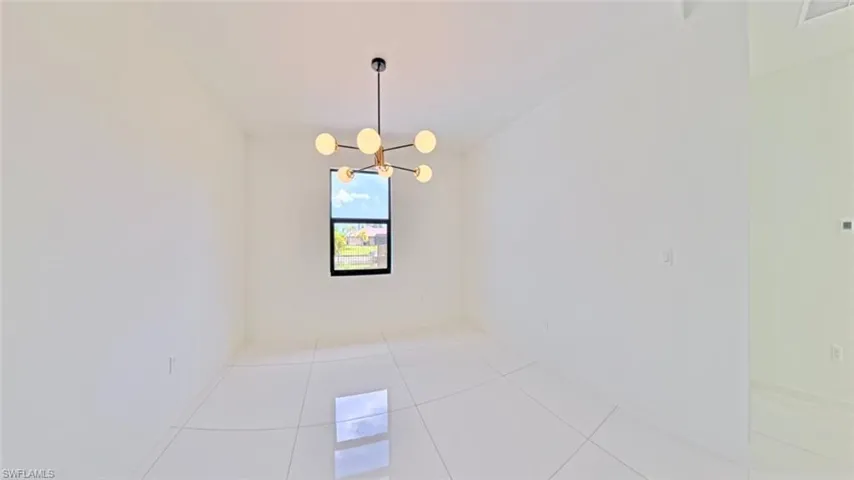 Unfurnished room with tile patterned flooring and a chandelier