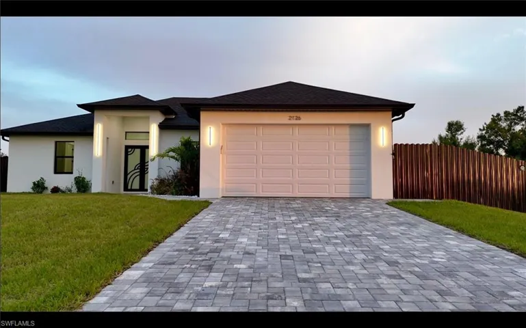 Prairie-style home with decorative driveway, stucco siding, an attached garage, and a shingled roof