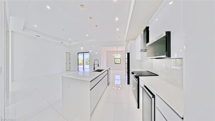 Kitchen featuring white cabinetry, pendant lighting, light tile patterned flooring, black electric range, and modern cabinets