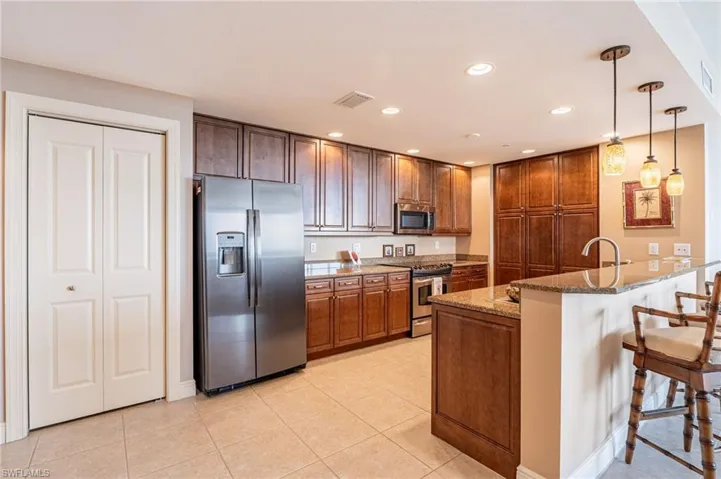 Kitchen with pendant lighting, appliances with stainless steel finishes, stone countertops, kitchen peninsula, and a kitchen breakfast bar