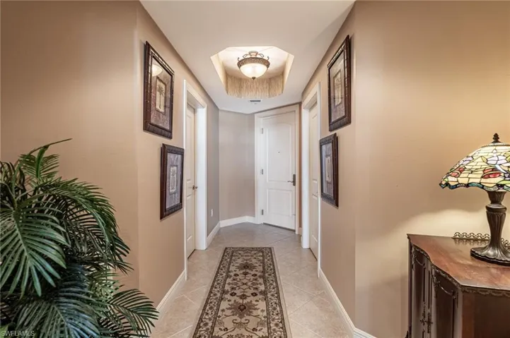 Hallway with a raised ceiling and light tile patterned floors