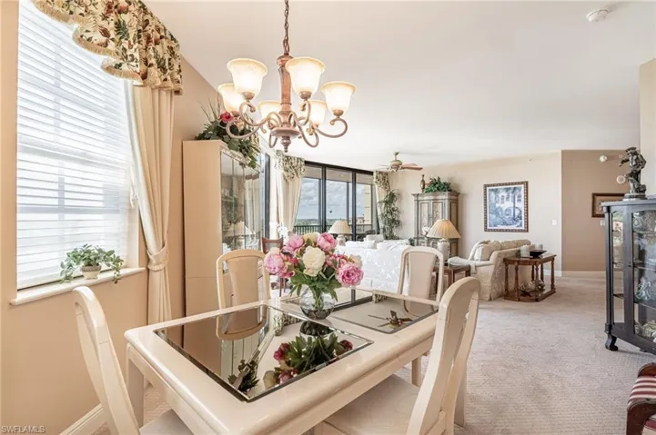 Carpeted dining space with ceiling fan with notable chandelier
