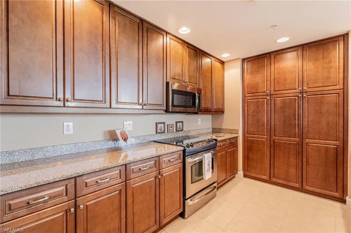 Kitchen with light tile patterned flooring, stainless steel appliances, and light stone countertops