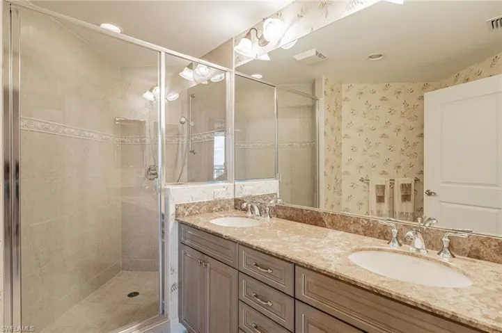 Bathroom featuring walk in shower and dual vanity