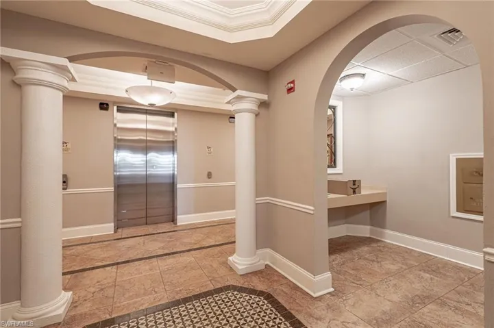 Bathroom with elevator, tile patterned floors, and decorative columns