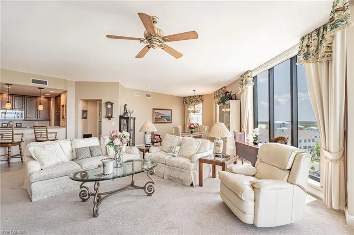 Living room featuring ceiling fan with notable chandelier and light colored carpet